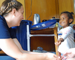 Volunteer Rose Wilson demonstrates the new water filter's clean water to a young Fijian patient