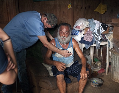 medical volunteer examines patient in home