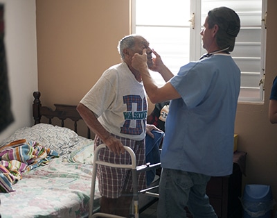 medical volunteer examines patient in home