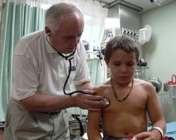 John P. Howe, III, M.D. President and CEO of Project HOPE, examines a young patient in Indonesia following the 2004 tsunami