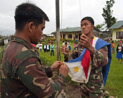 Members of the Philippine army raise a flag at San Antonio elementary school, the site of a health outreach clinic 