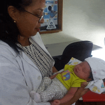 Doctor holds newborn in Dominican Republic health clinic.