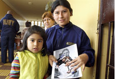 Maria Vilches Vasquez with child holding photographs