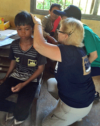 Project HOPE volunteer nurse practitioner Susan Opas checks a young patient's ears on Pacific Angel 16-2