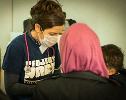 Project HOPE volunteer Dr. Corey Kahn cares for a migrant patient on her first day at the Immigrant Transit Center