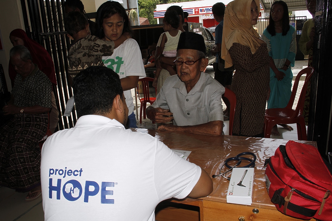 Medical volunteer talking to Indonesian man in clinic