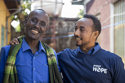 Two men, a volunteer and local healthcare worker, smiling
