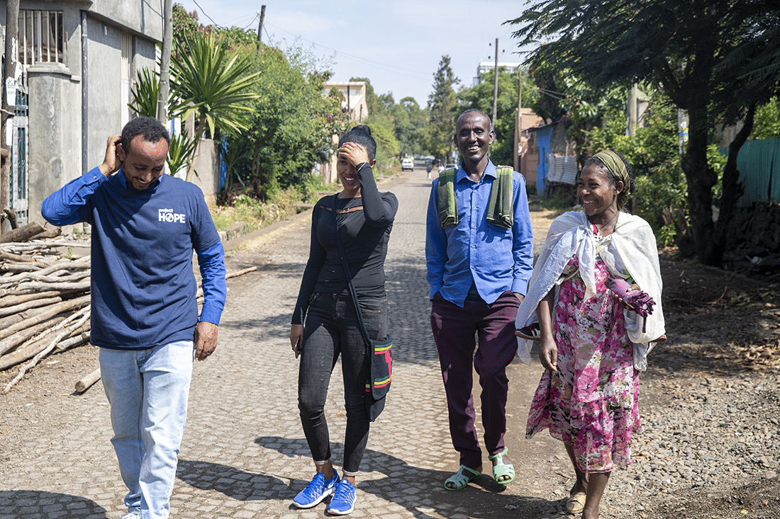 A pair of health care workers walk with a pair of beneficiaries. The beneficiaries are now working as volunteer Community Resource Persons helping others connect with HOPE.