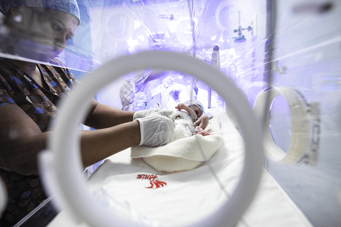 Nurse treating a baby in an incubator