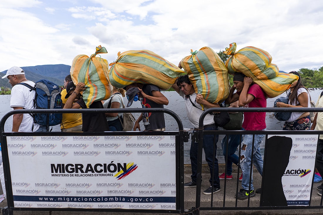 People crossing the border carrying supplies. 