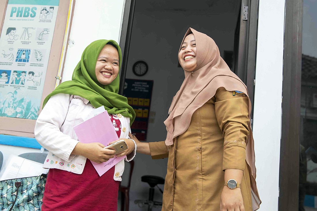 Two women smiling standing in a doorway.