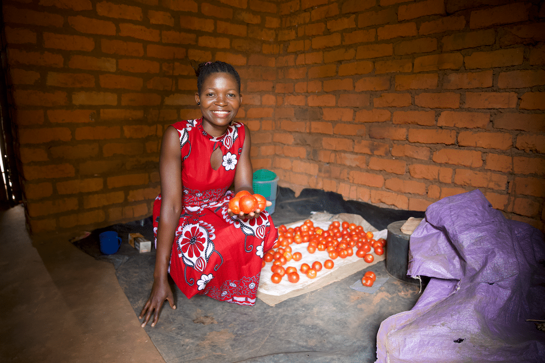 Linda, 23, smiling at the camera while holding fresh produce that she is selling