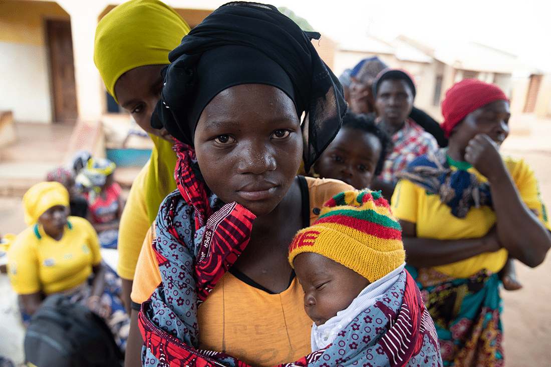 Portrait of a woman holding her baby while waiting in line in Malawi