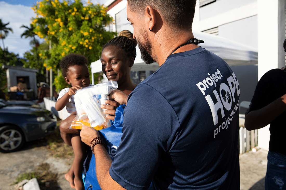 Volunteer leader gives a hygiene kit to a mother and baby in the Bahamas.