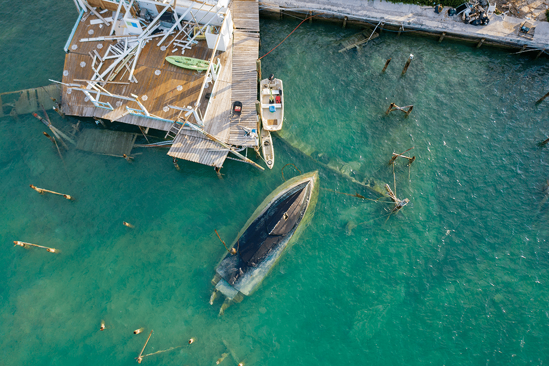 Hurricane destruction in Bahamas with a boat overturned in the ocean.