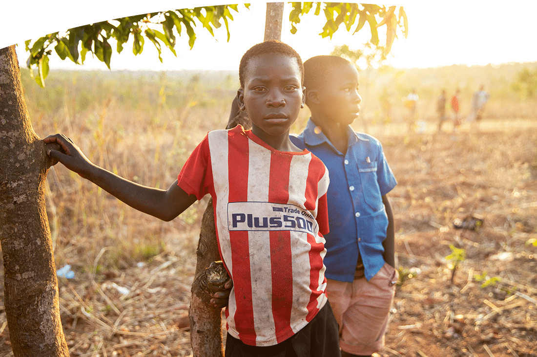 Portrait of two boys in Malawi standing by a tree.