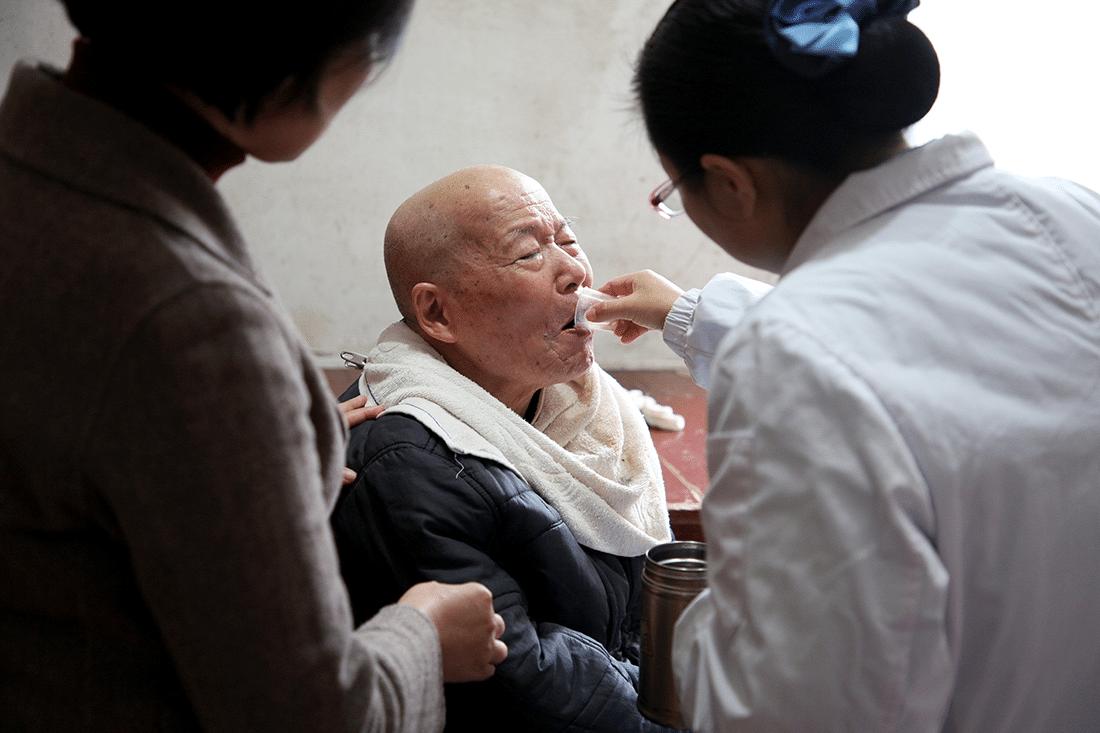 Elderly man is fed his medicine.