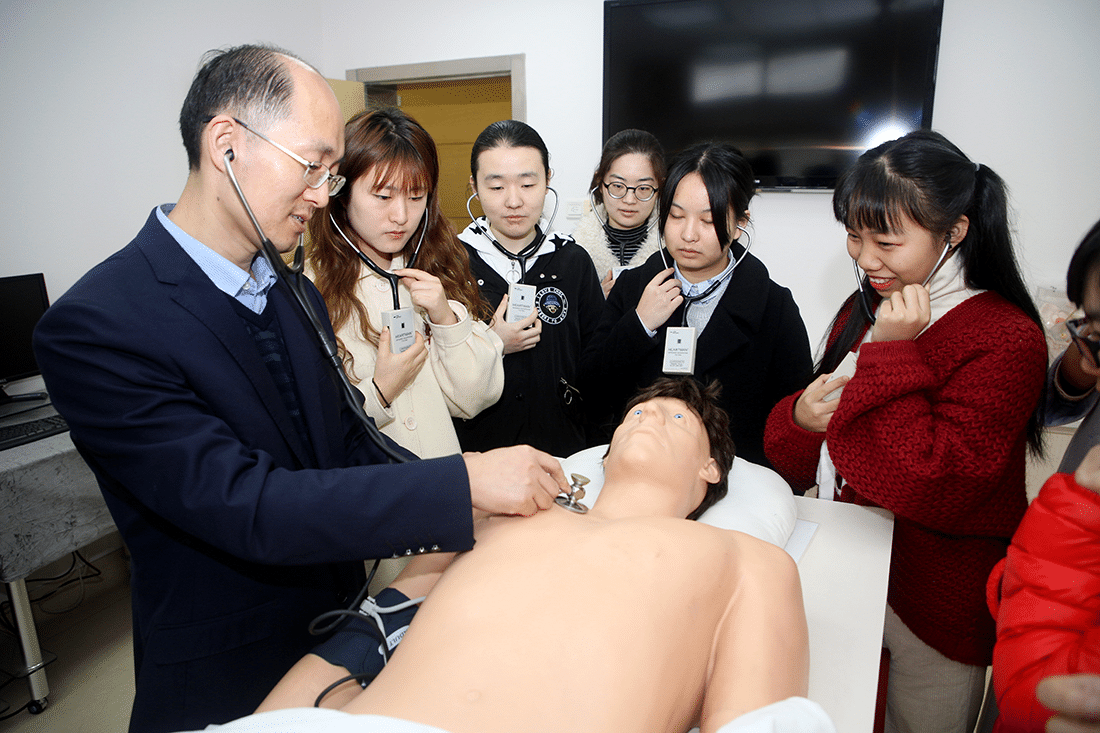 Chinese doctor working on a dummy patient teaching students around him.