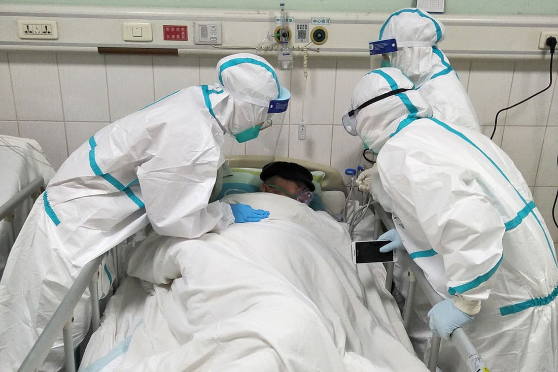 Doctors surround the bed of a sick patient.