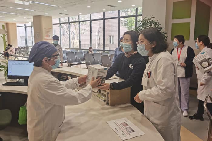 Nurses wearing protective masks distribute masks to others in a hospital.
