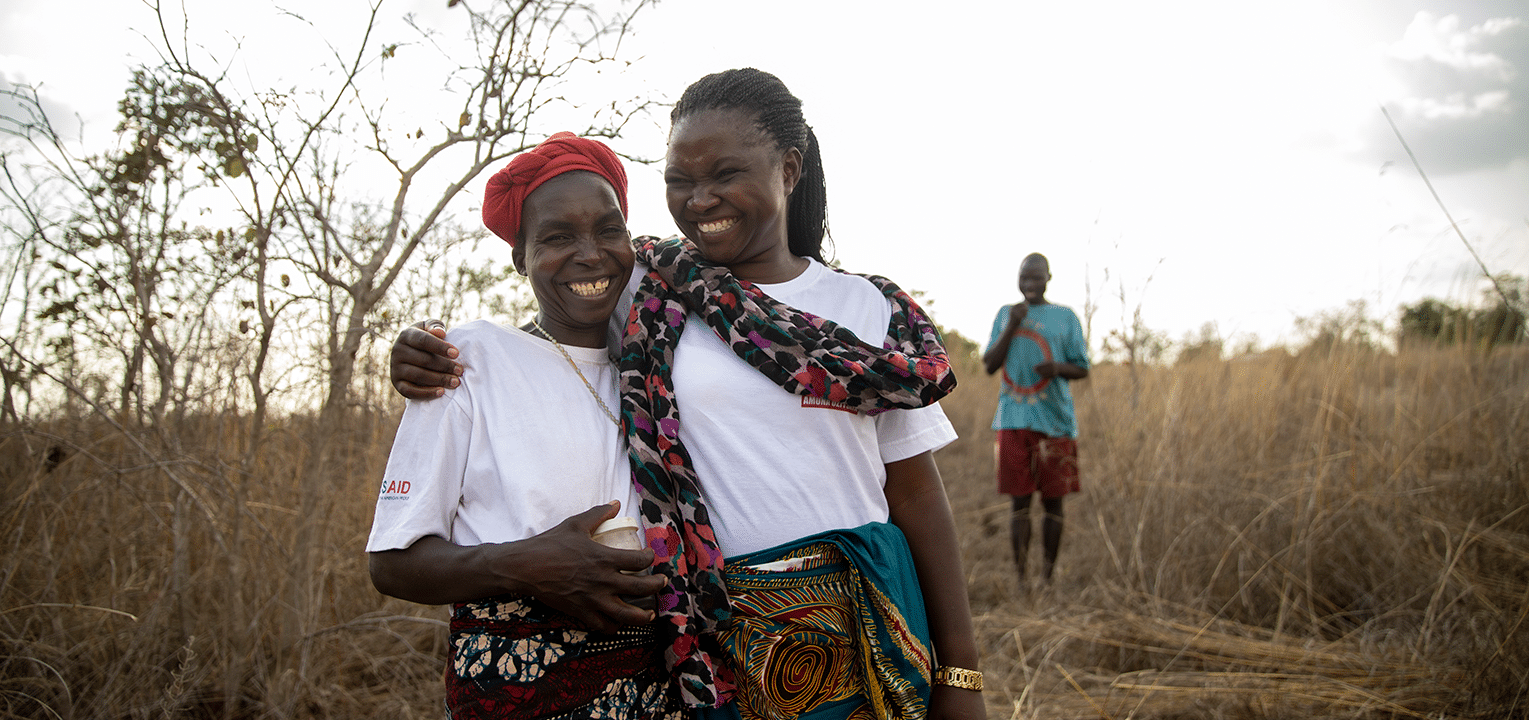 Two women hugging in a village in Africa.