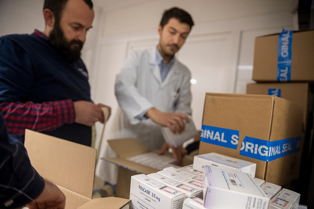 Two men unload a shipment of medicines.