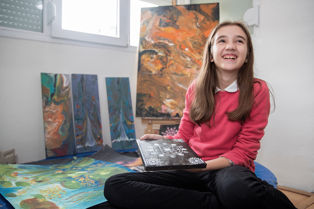 A young girl shows off her artwork.