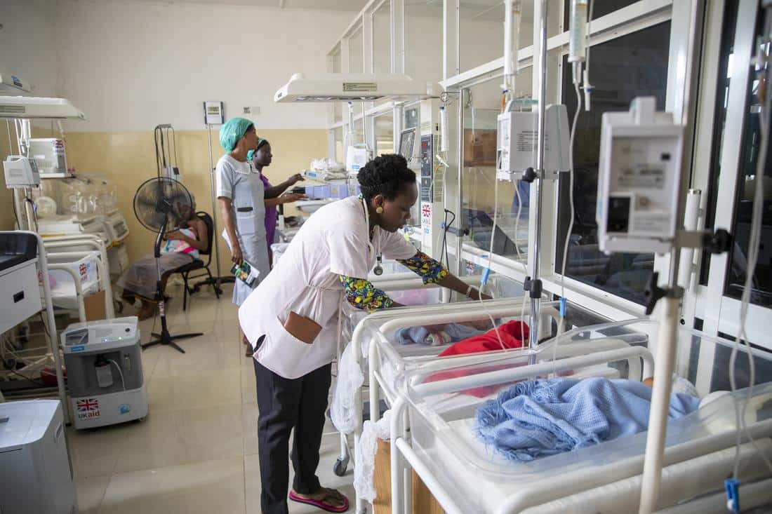 Pediatrician examines newborn baby on ward