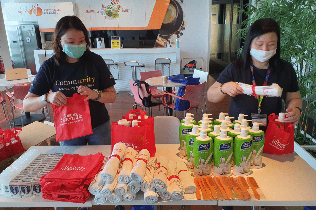 Two women packing hygiene supplies into sample bags.