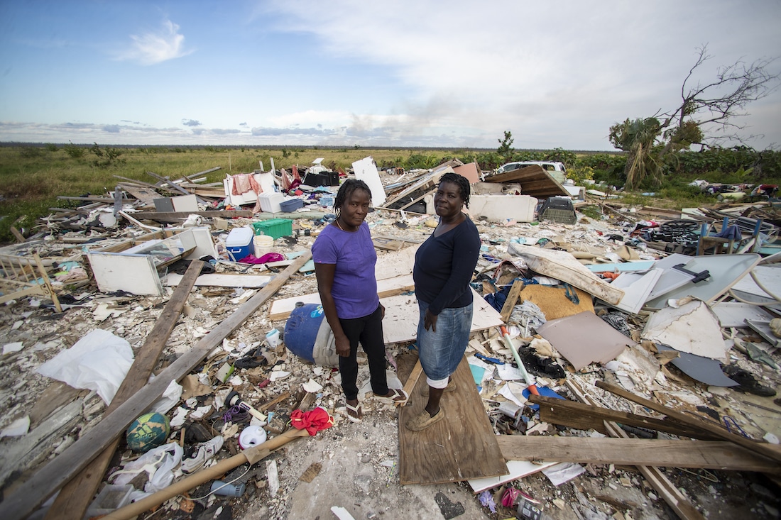 Women standing in rubble after Hurricane Dorian