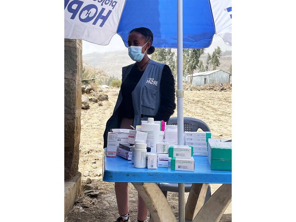 woman in Project HOPE gear and mask standing beside medical equipment in Ethiopia