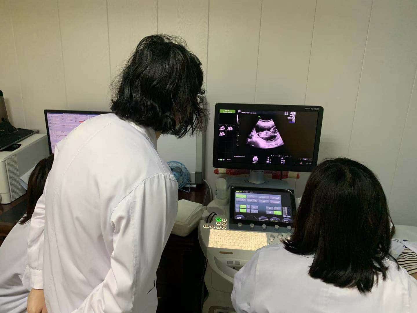 computer screen of an ultrasound with three women looking at the image