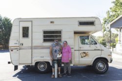 Two people standing in front of an RV