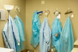 six sets of medical robes hanging up at a hospital.