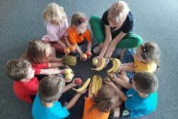 children playing with fruit in a circle.