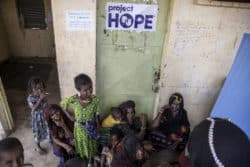 children and women standing around a project hope door