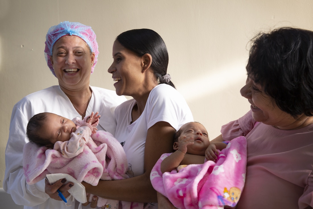 Three women laughing while holding two babies.