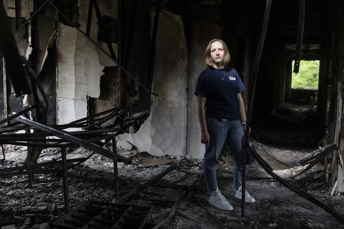 a woman stands among rubble in a dark-lit room in Ukraine