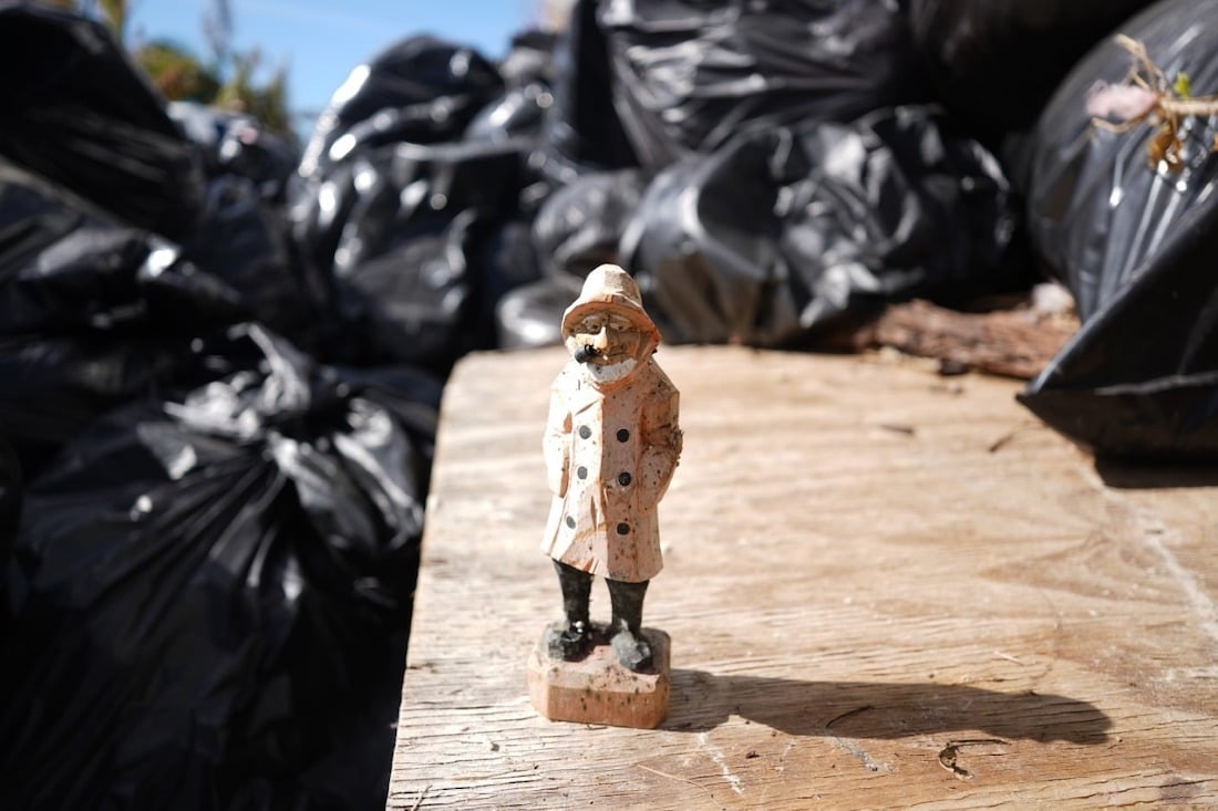 close-up shot of a wooden sailor figurine surrounded by trash bags