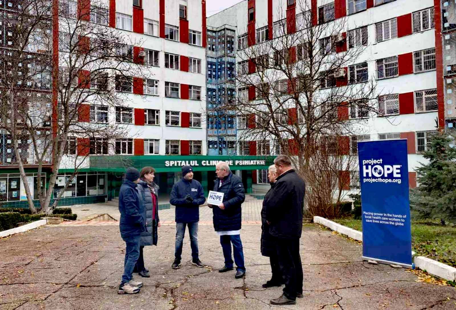 six people speaking outside of a hospital in Ukraine