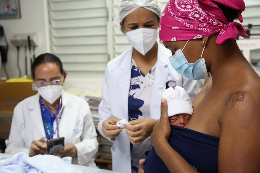 a mother holding their newborn surrounded by doctors