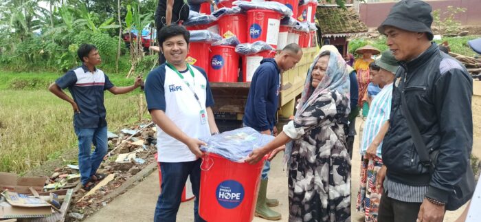 Project HOPE staff and community members carrying supplies in buckets in Indonesia