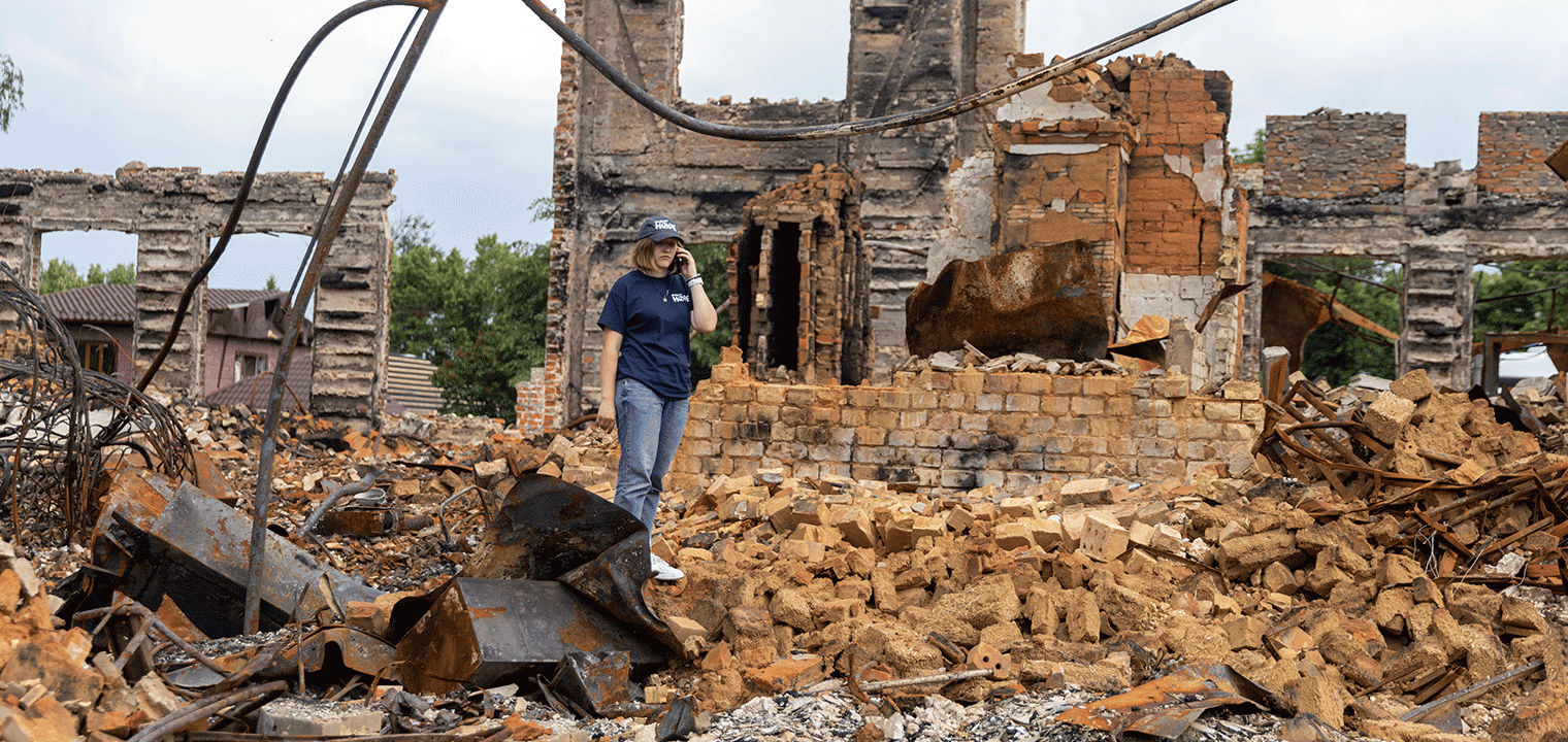 woman standing in rubble in Ukraine