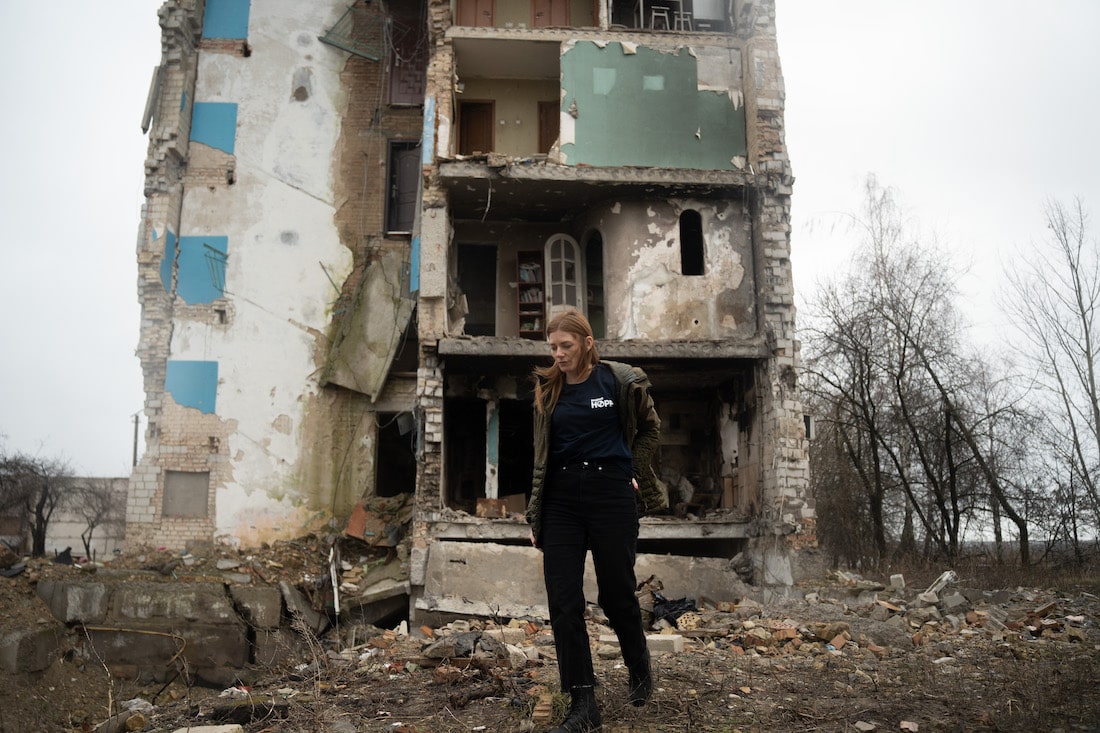 Woman standing in front of a destroyed building in Ukraine
