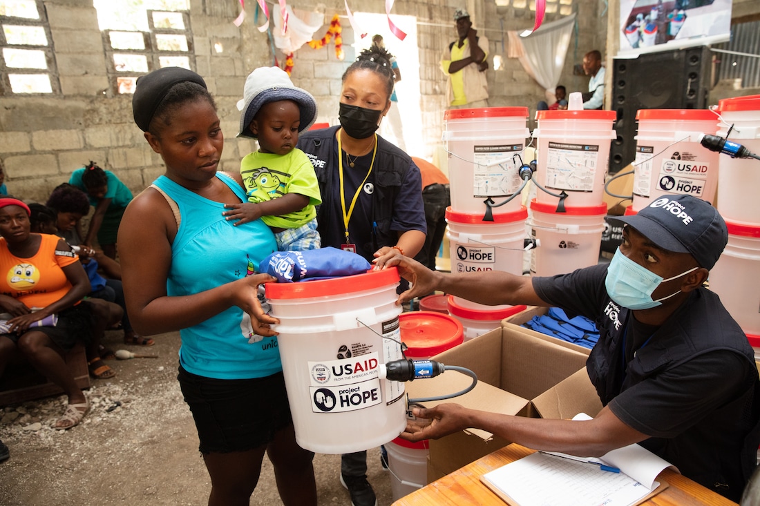 a woman holding her child along with two healthcare workers in Haiti