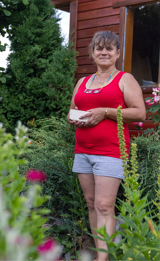 woman in red tank top stands among a garden