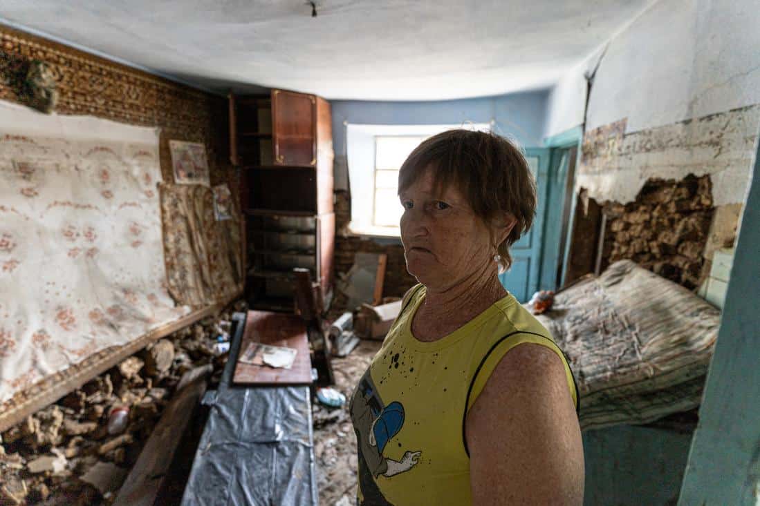 Woman in yellow shirt standing in a destroyed home due to flooding in Ukraine