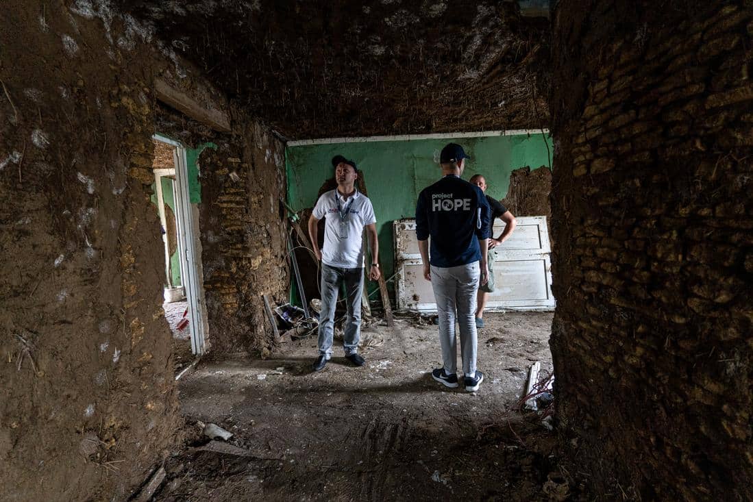 Three people standing in destroyed home in Ukraine