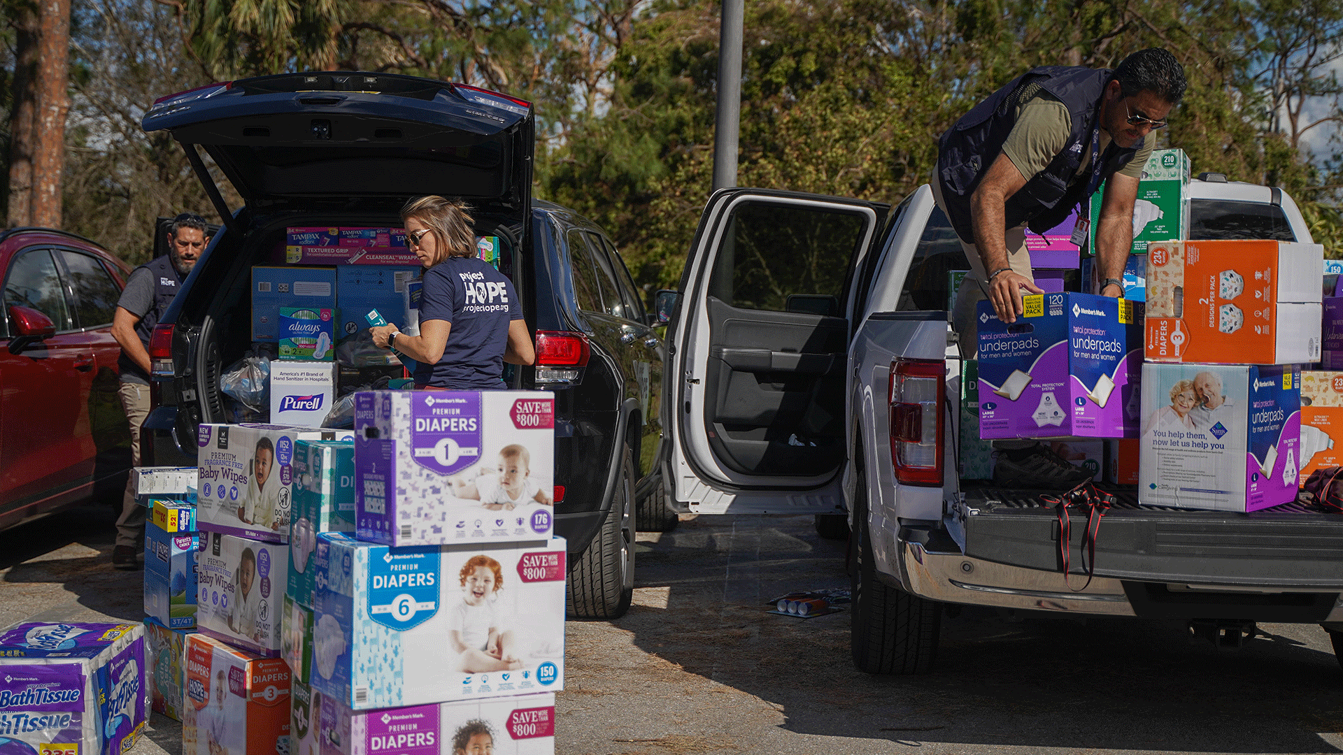 three people unloading baby supplies out of trucks