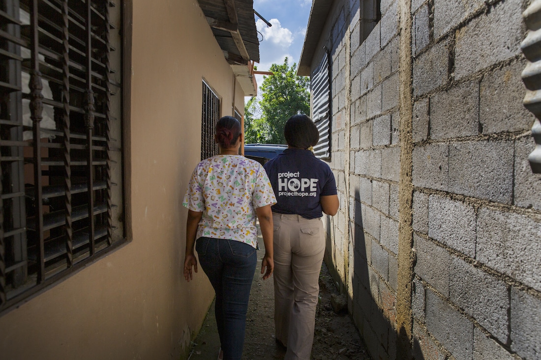 Camera following behind two women walking down an alley.